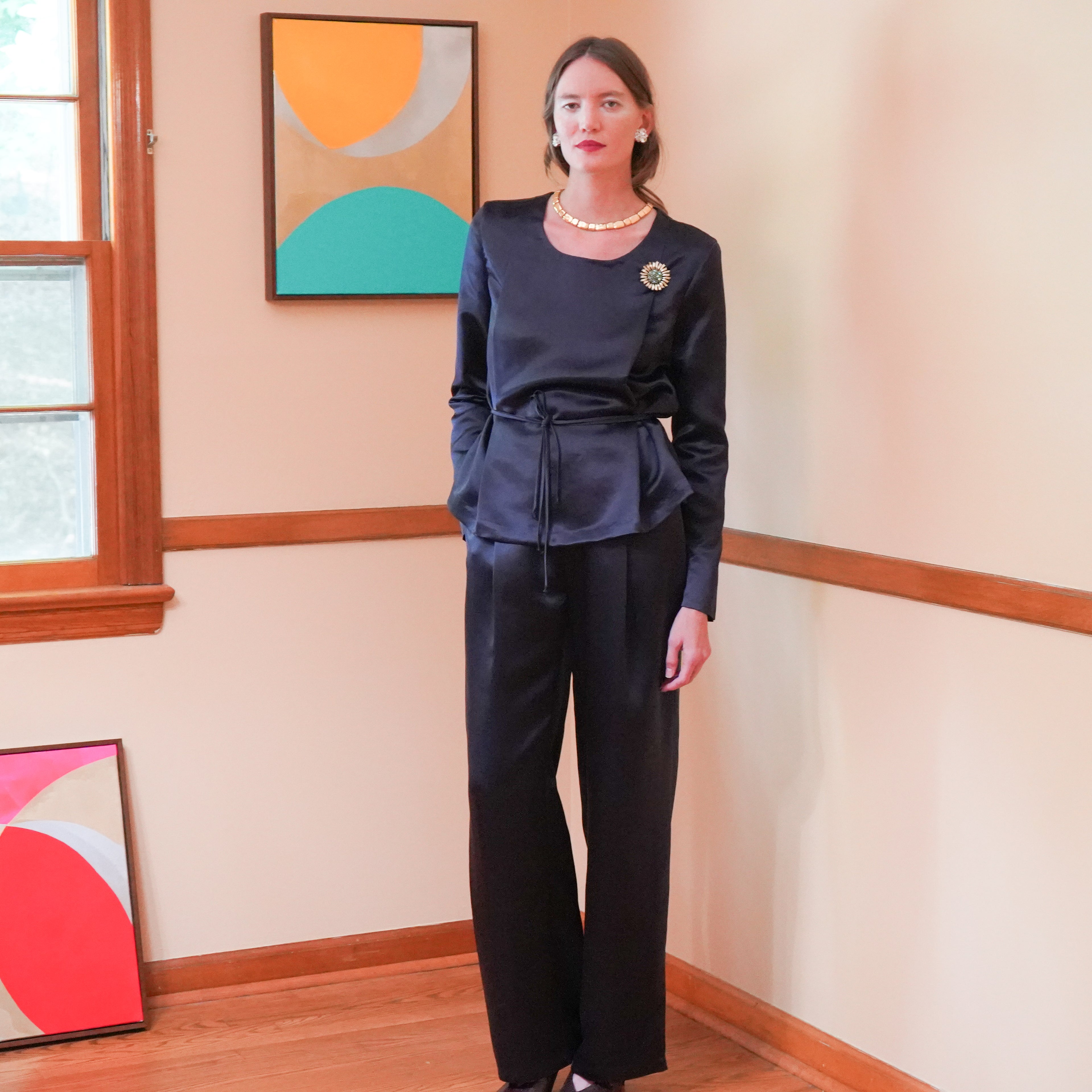 Dark navy satin long-sleeve top with a waist tie and matching dark wide-leg trousers.